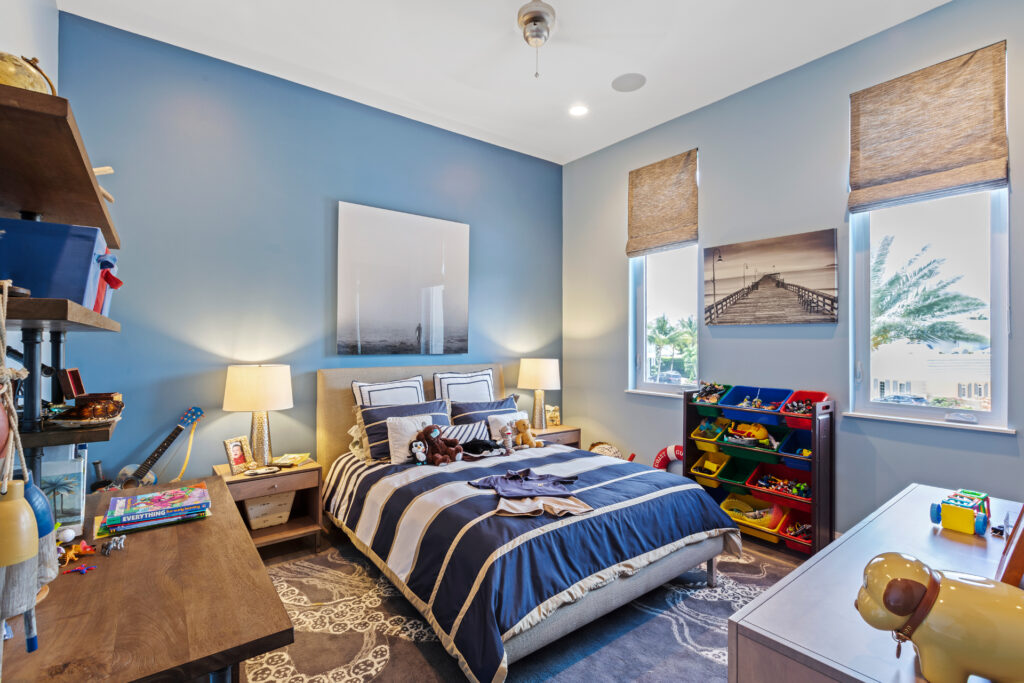 Baby blue kid’s bedroom with a study table, fluffy bed with blue bedsheets, and toys