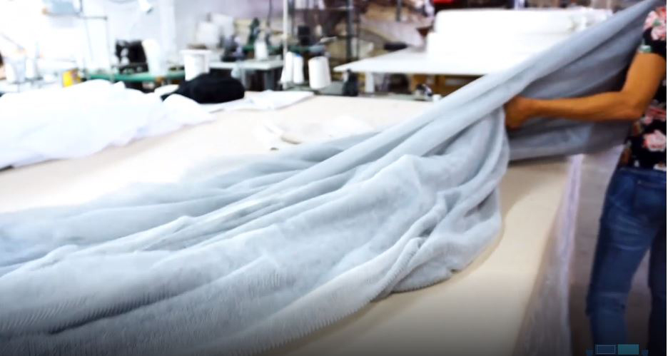 Woman laying out a off-white blanket on a white table
